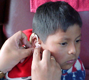 Niño sordo con audifono para escuchar
